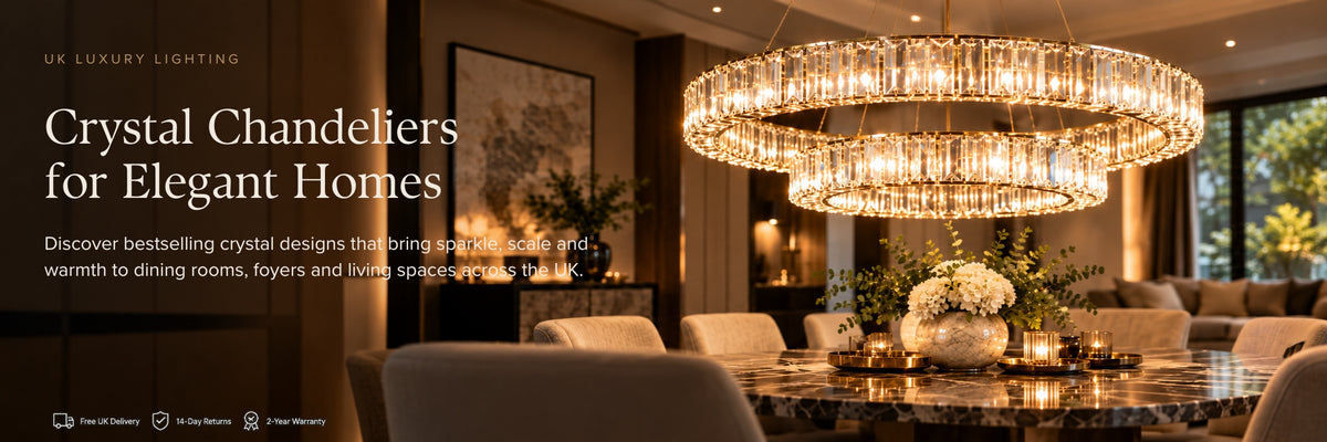 A luxury dining room interior with a large circular crystal chandelier hanging over a marble dining table. The scene includes upholstered chairs, decorative floral arrangements, warm ambient lighting, and a dark wood wall with text overlay reading 'Crystal Chandeliers for Elegant Homes' and 'UK LUXURY LIGHTING'.