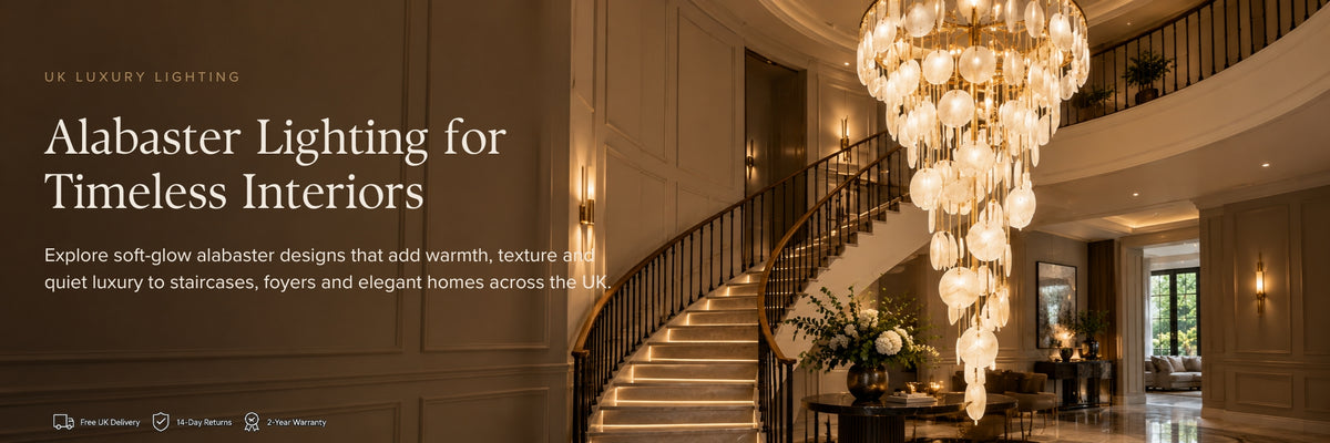 Promotional banner for UK Luxury Lighting featuring a large, elegant alabaster chandelier with cascading crystal-like drops hanging in a grand staircase foyer. The left side has a dark overlay with white text reading 'Alabaster Lighting for Timeless Interiors' and 'UK LUXURY LIGHTING'.